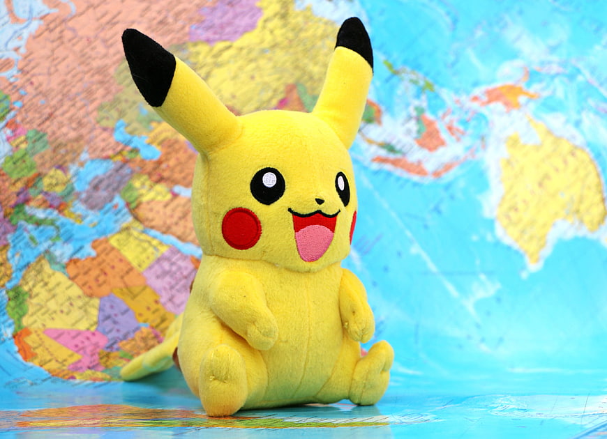 Cute Pikachu plush toy sitting on a colorful world map