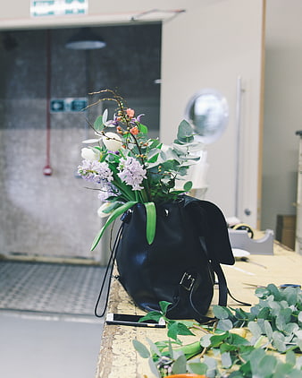 Floral arrangement in black leather bag on wooden table