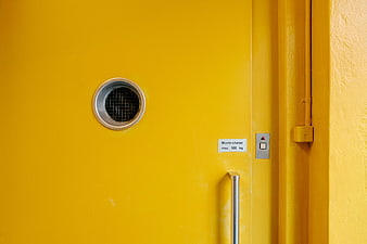 Close-up of a yellow freight elevator door with handle and call button