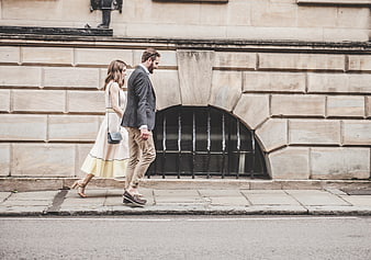 Stylish couple walking on city sidewalk