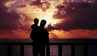 Silhouette of Father and Son Watching Sunset Over Ocean