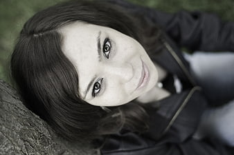 Close-up portrait of young woman lying on grass looking up