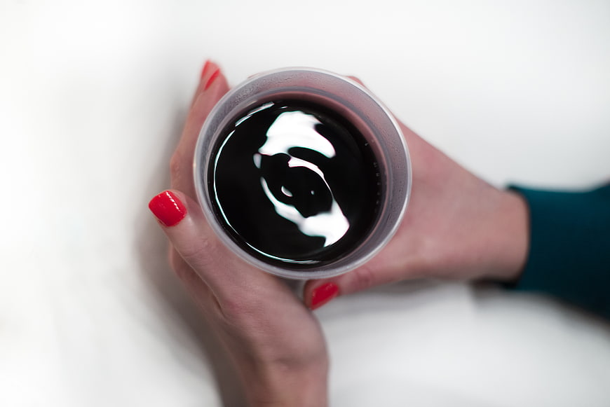 Hands holding a cup of black coffee from above
