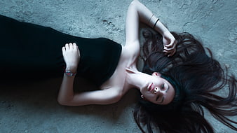 Young woman in black dress lying on concrete floor