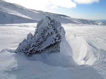 Snow-covered rock formation in vast winter mountain landscape