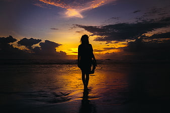 Silhouette of Woman Walking on Beach at Sunset