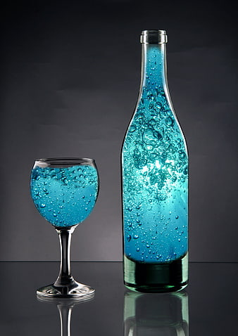 Blue Sparkling Liquid in Glass Bottle and Wine Glass