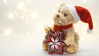 Cute teddy bear in Santa hat holding red star Christmas ornament