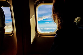 Silhouette of Woman Looking Out Airplane Window at Clouds