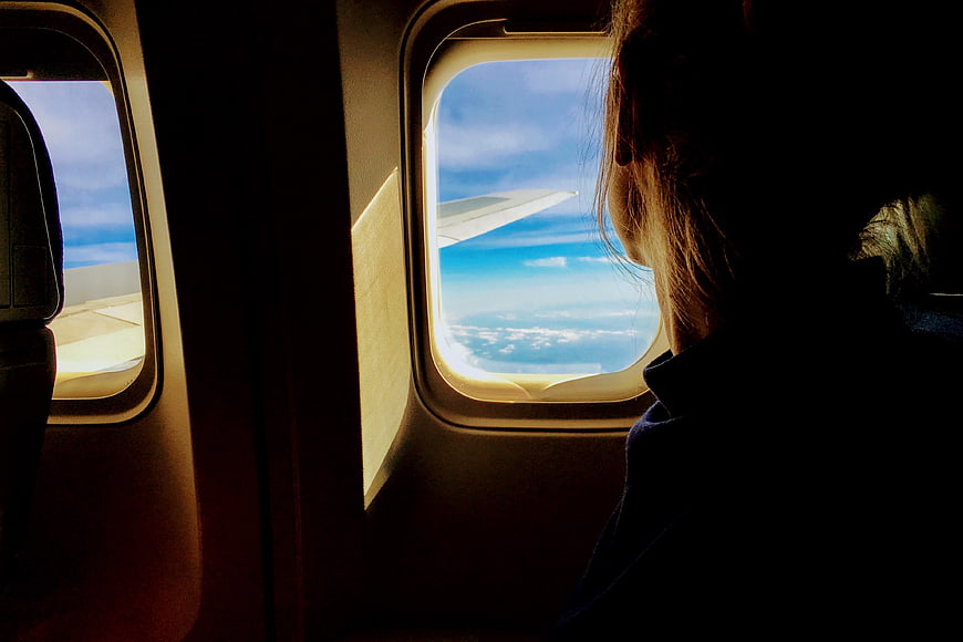 Silhouette of Woman Looking Out Airplane Window at Clouds