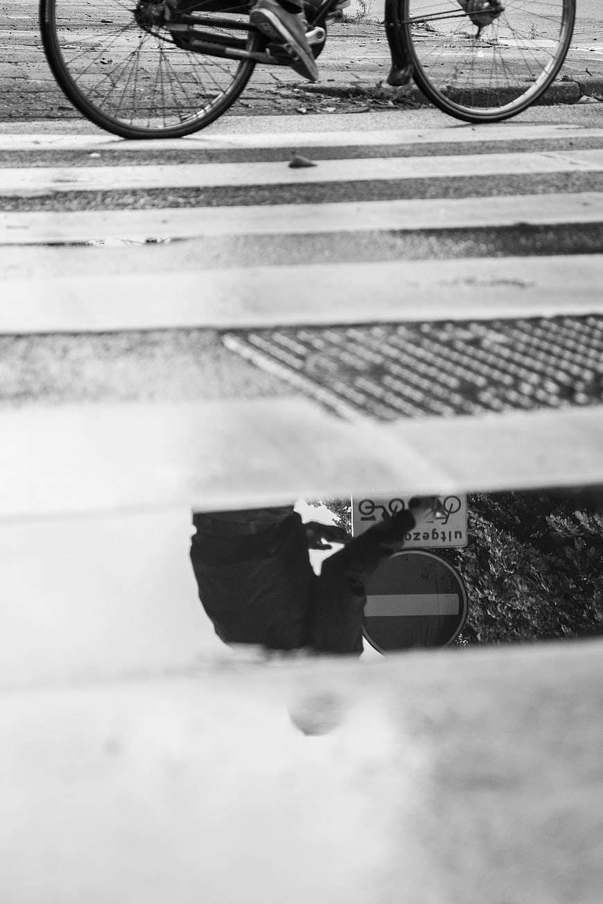 Black and white street photography of bicycle reflection in puddle