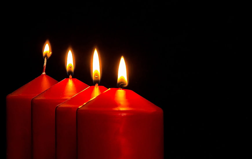 Four Lit Red Advent Candles on Black Background