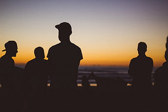 Silhouettes of friends watching sunset at the beach
