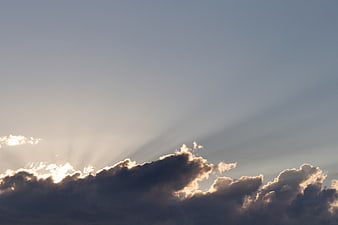 Dramatic Sun Rays Breaking Through Dark Clouds in Blue Sky