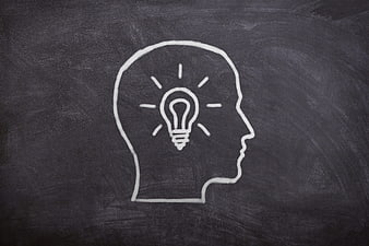 Chalk drawing of human head profile with lightbulb idea symbol on blackboard