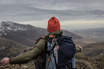 Hiker with backpack looking at mountain landscape