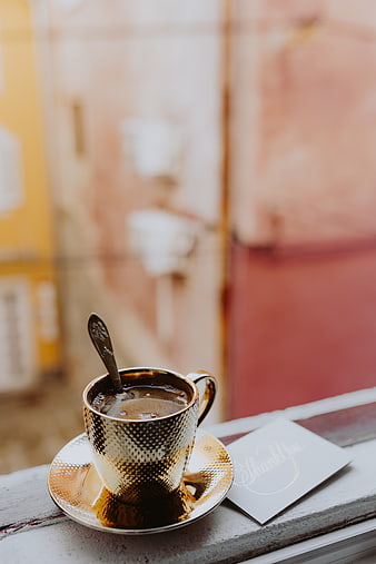 Golden Coffee Cup on Window Sill with Blurred Background