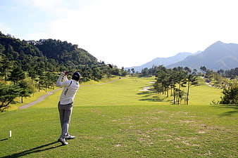 Golfer Swinging Driver On Scenic Mountain Golf Course