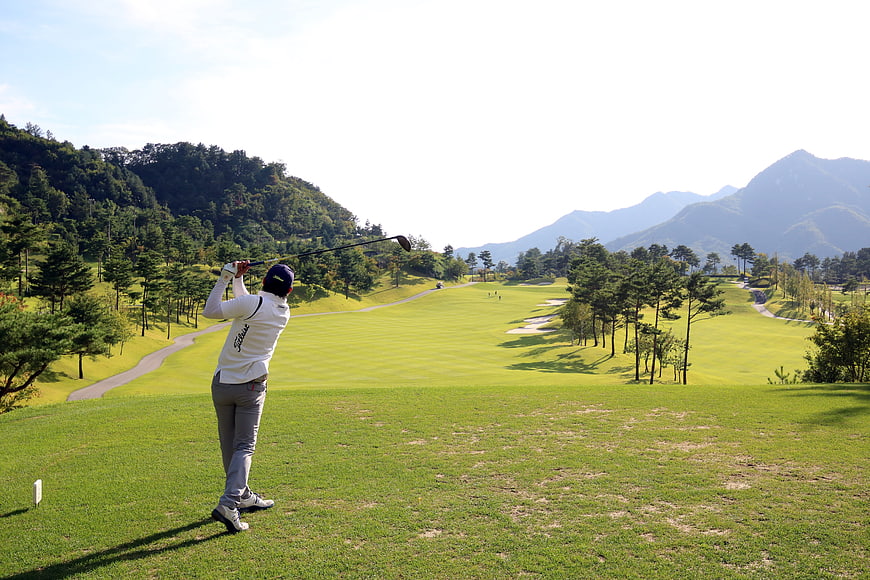 Golfer Swinging Driver On Scenic Mountain Golf Course