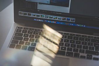Laptop keyboard with sunlight glare and photo editing software