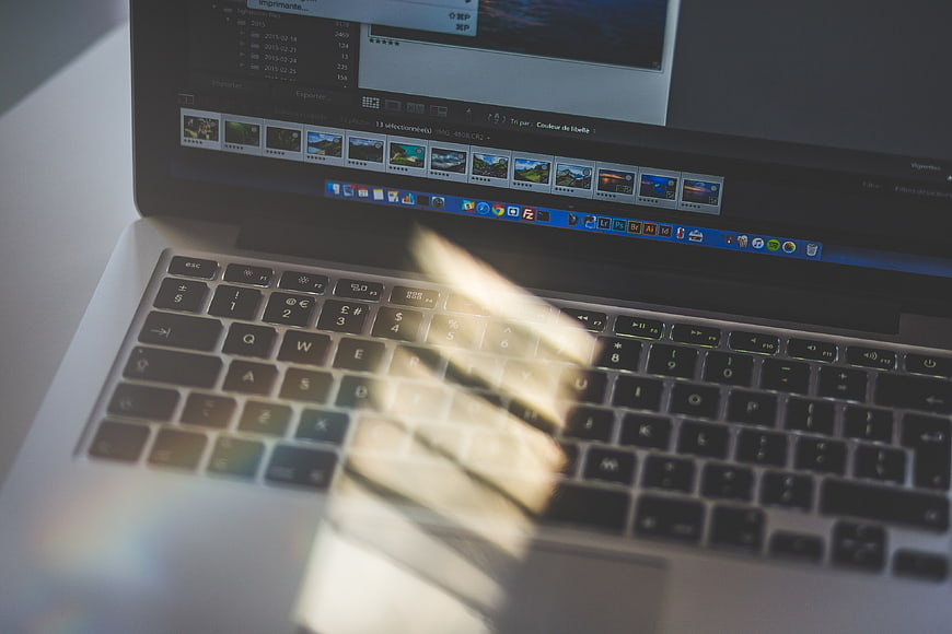 Laptop keyboard with sunlight glare and photo editing software