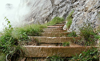 Mossy stone steps leading up a steep, misty mountain cliff face