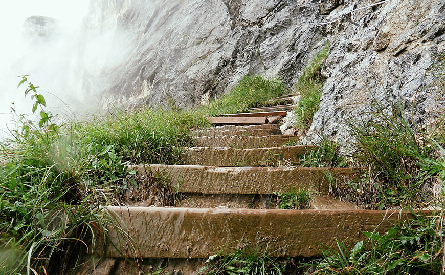 Mossy stone steps leading up a steep, misty mountain cliff face