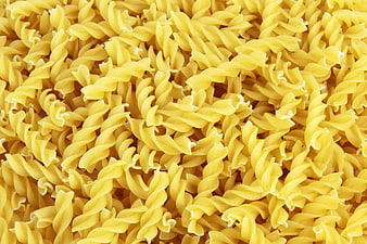 Close-up texture of uncooked yellow rotini pasta