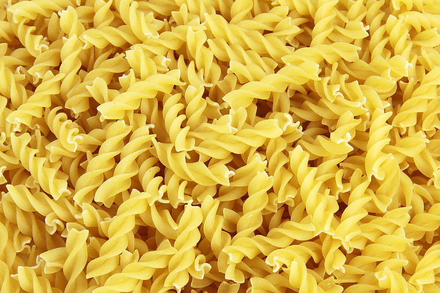 Close-up texture of uncooked yellow rotini pasta