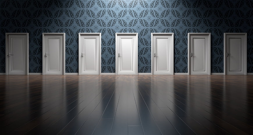 Row of white doors in dark patterned room with wooden floor