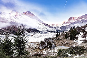 Snowy mountain landscape with winding road and pine trees