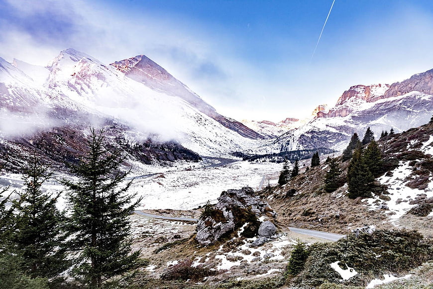 Snowy mountain landscape with winding road and pine trees
