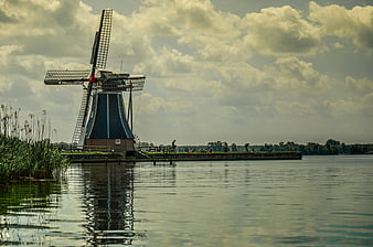 Traditional Dutch Windmill by Water with Cloudy Sky