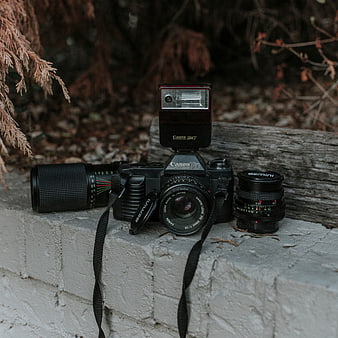 Vintage Canon T50 Camera with Flash and Lenses on Brick Wall
