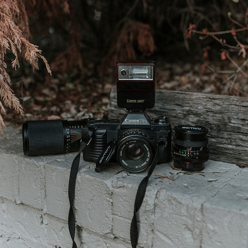 Vintage Canon T50 Camera with Flash and Lenses on Brick Wall