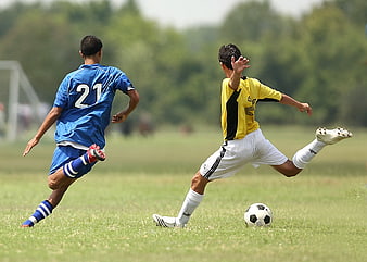 Two young soccer players competing for the ball on a grass field