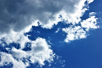 Dramatic white clouds against deep blue sky background