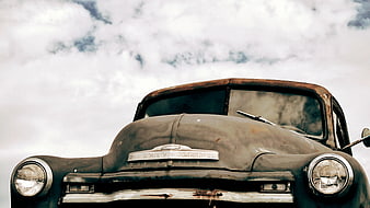 Front view of vintage rusty Chevrolet truck against cloudy sky