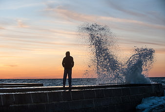 Silhouette of Man Watching Waves Crash at Sunset