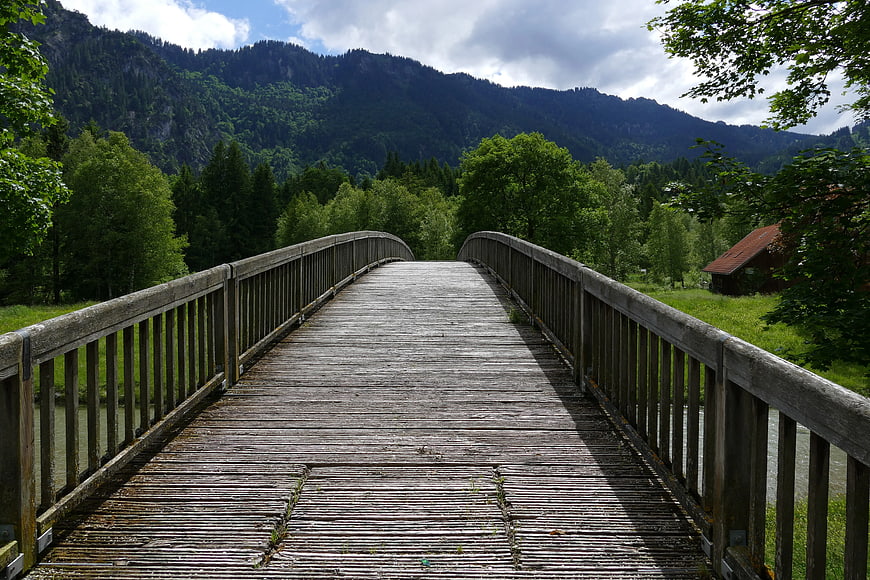 Wooden Bridge Leading to Mountain Forest Landscape
