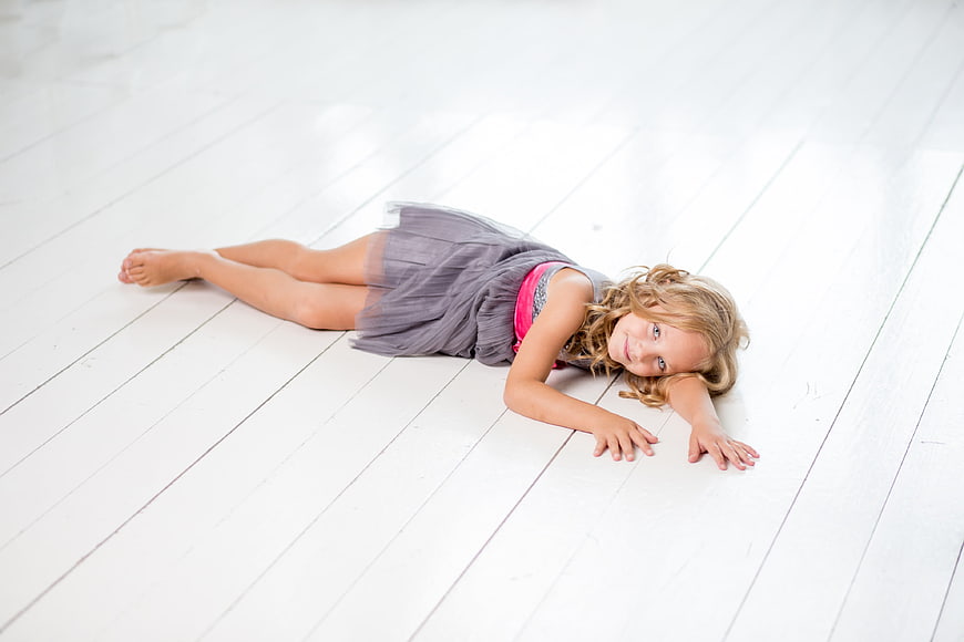 Cute little girl lying on white wooden floor