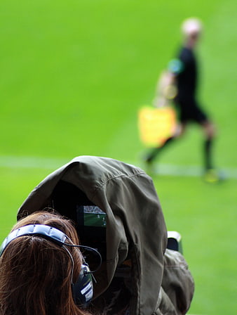 Videographer filming soccer match on green field