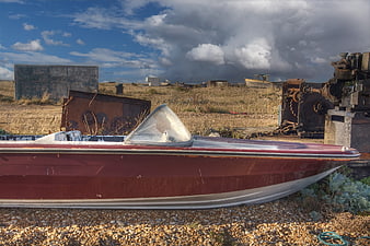 Abandoned Red Speedboat on Gravel Beach