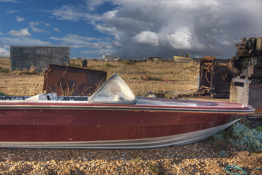 Abandoned Red Speedboat on Gravel Beach