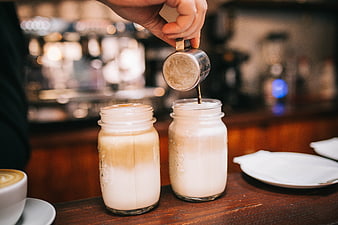 Barista pouring coffee into mason jar milk drinks