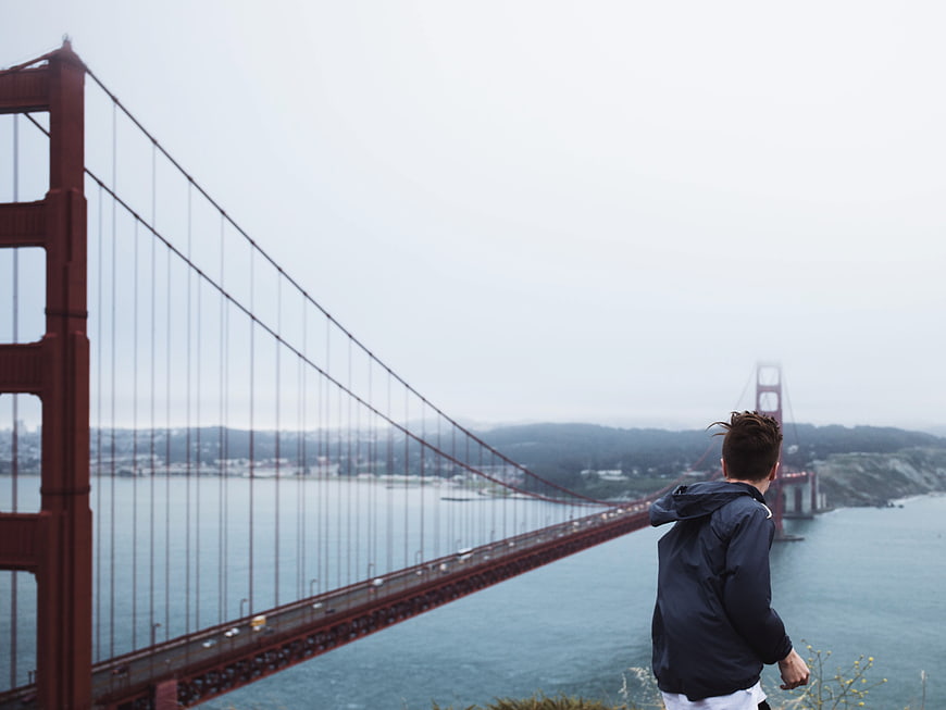 Man Looking at Golden Gate Bridge on Foggy Day