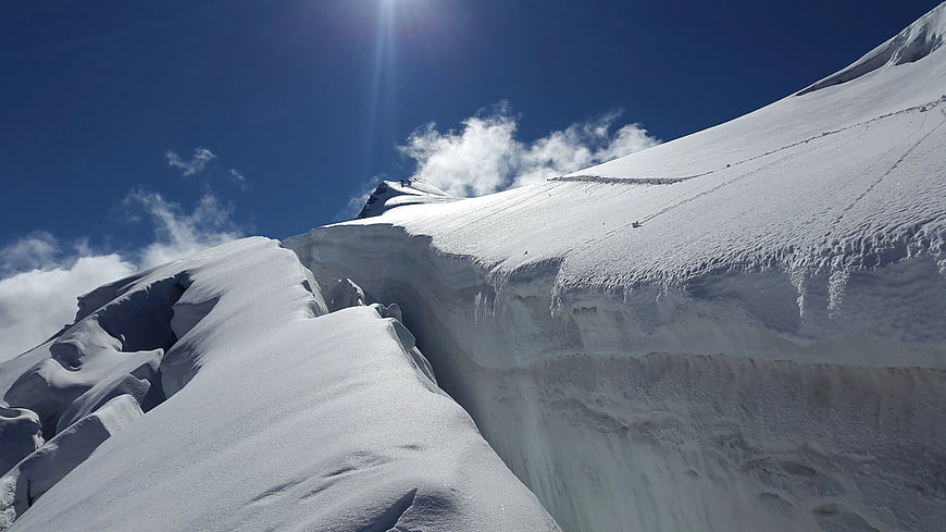 Snowy Mountain Ridge with Deep Crevasse and Blue Sky
