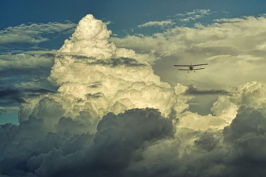 Small Biplane Flying Through Dramatic Clouds