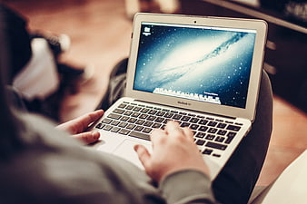 Person typing on MacBook Air laptop on lap