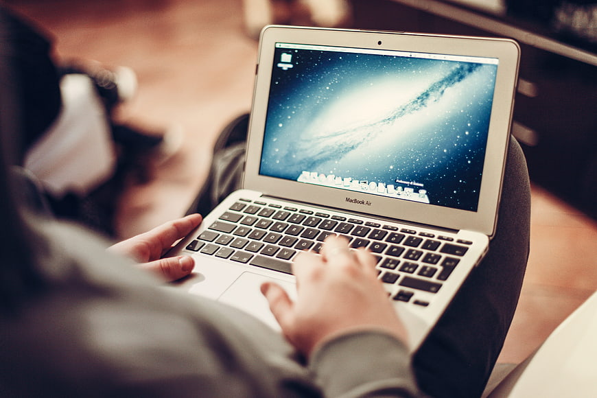 Person typing on MacBook Air laptop on lap